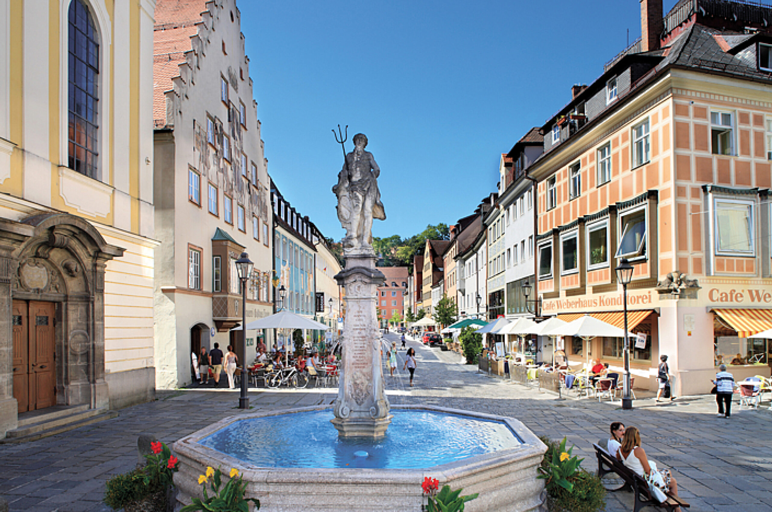 Brunnen auf einem Platz mit Cafe.